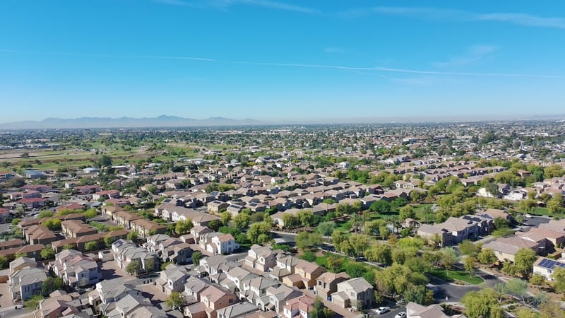 Aerial view of a Phoenix-area neighborhood with tile roofs and desert mountains beyond